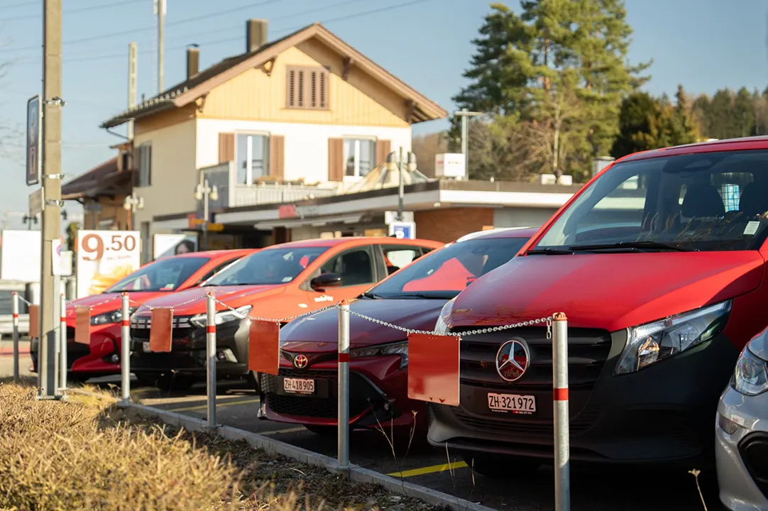 Row of car-sharing vehicles in the car park in front of the station building in a rural area.